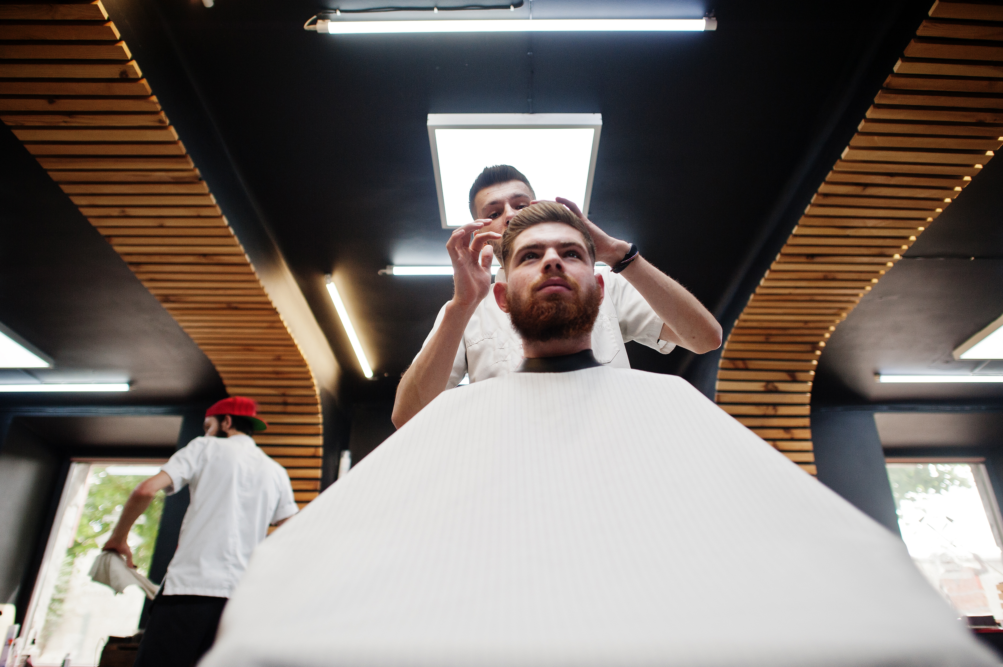 young-bearded-man-getting-haircut-by-hairdresser-while-sitting-chair-barbershop-barber-soul
